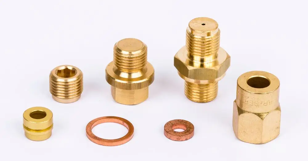 Verschiedene Messingfittings und Dichtungen auf einem weißen Hintergrund, geeignet für den Einbau in dem Danfoss Steuerungs-Set.